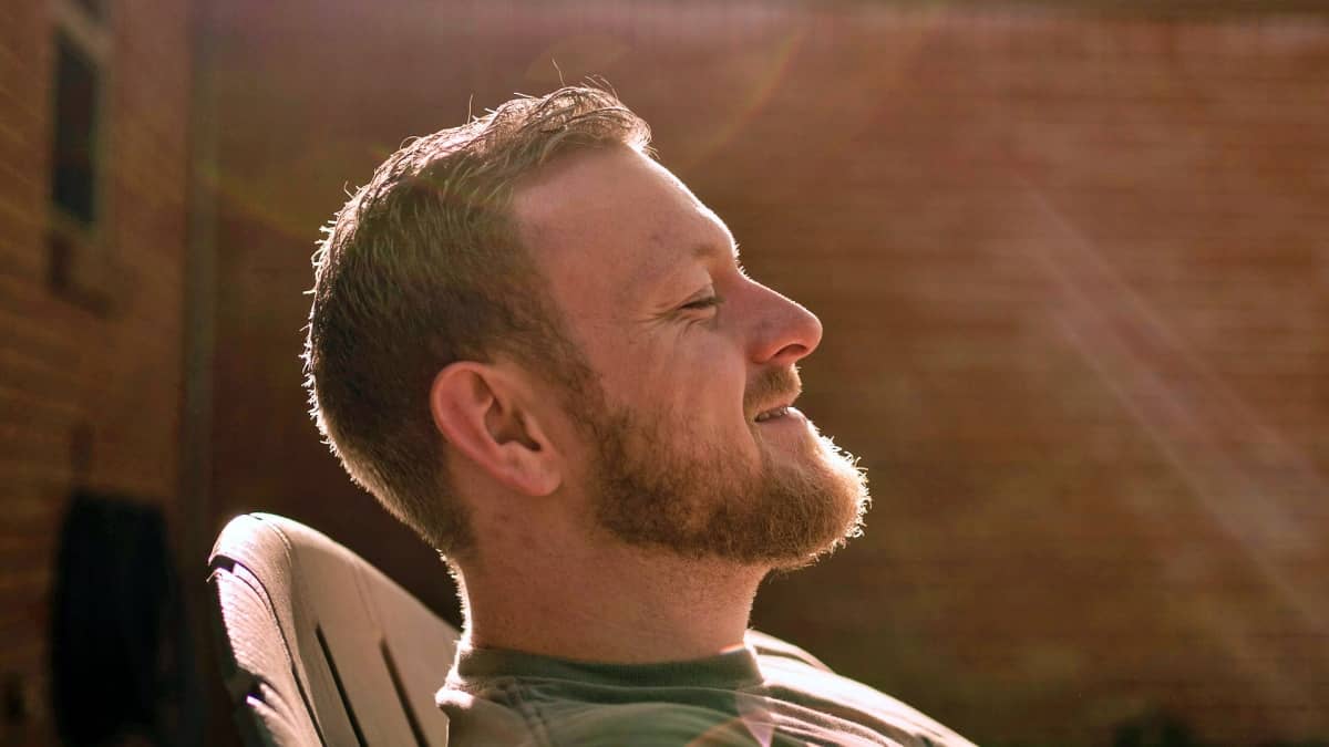 Photo of a happy adult man sitting outside in a lawn chair and soaking up the sun while enjoying a moment of mental clarity thanks to Brain Health supplements from World's Best Supplements.