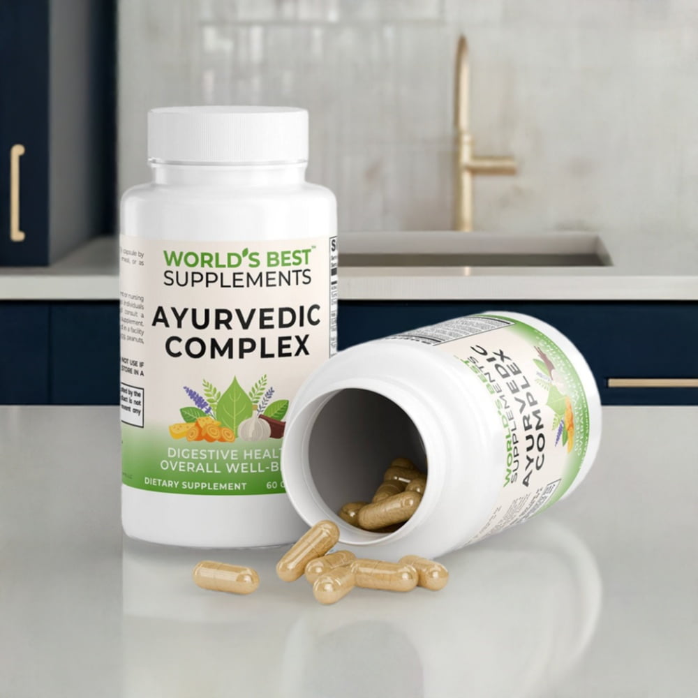 Two bottles of Ayurvedic Complex dietary supplement on a counter top with one tipped over with the lid off and capules pouring out onto the counter to show detail. By World's Best Supplements.